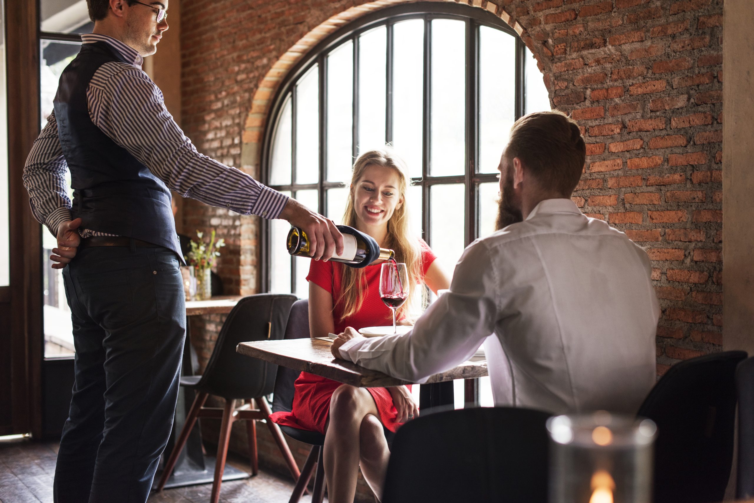 Restaurant server serving wine to seated customers