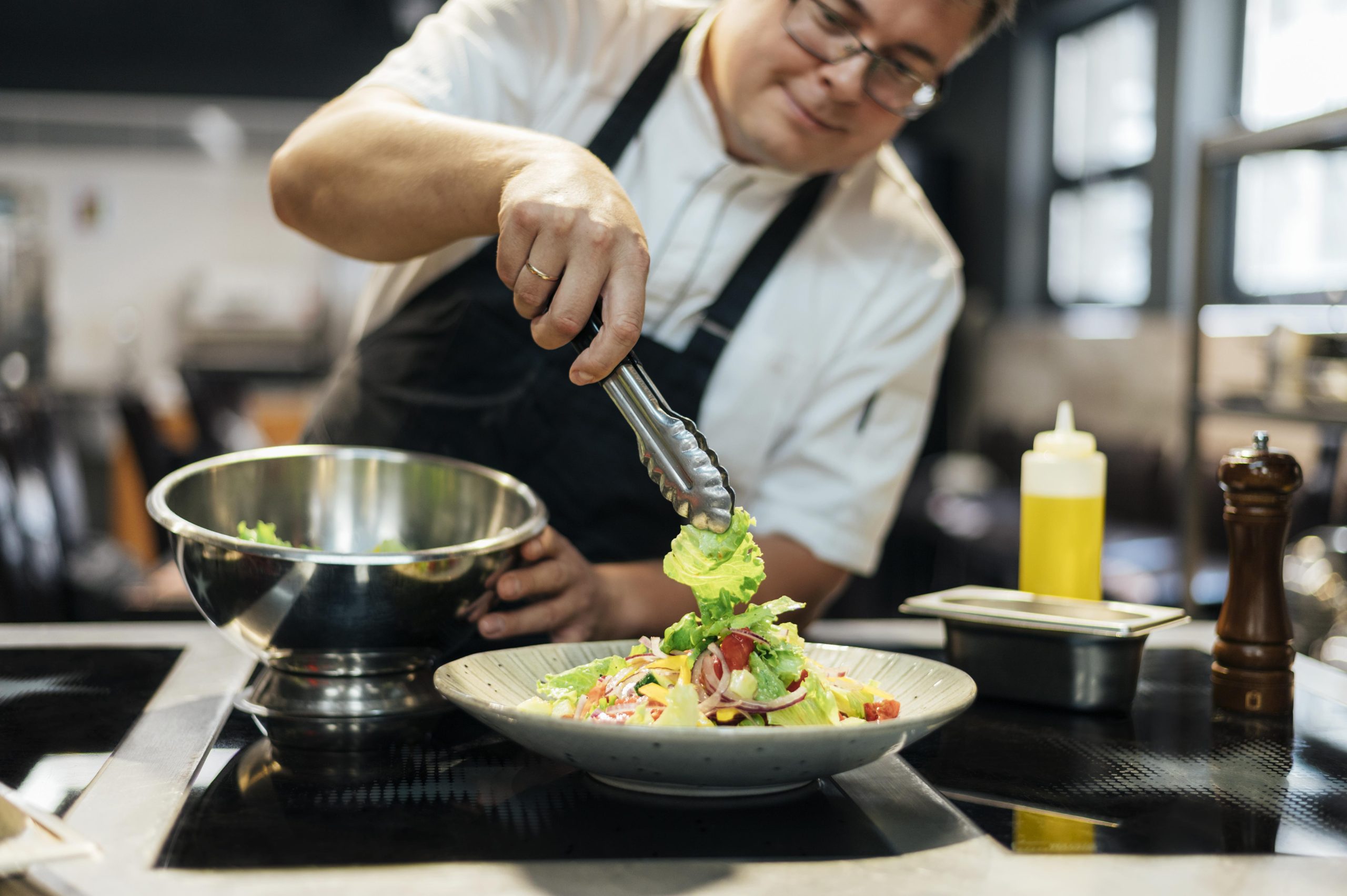 Chef concentrating while plating a dish in a professional kitchen